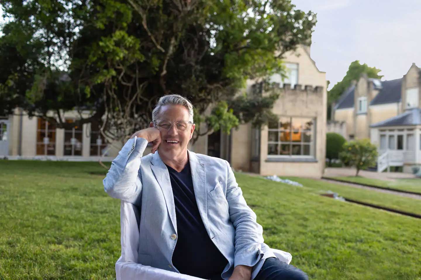 James Salmond, wearing a light linen jacket, sits in front of Ben Huon Manor.